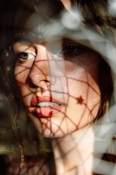 pexels photo 11760375 11760375 Close-up portrait of a woman with dreamcatcher shadows on her face, evoking mystery and introspection.