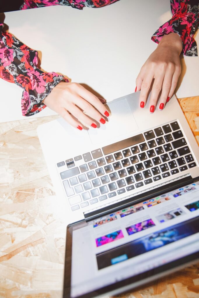 pexels photo 3747068 3747068 Overhead view of woman using laptop, showcasing red manicured nails and floral blouse in a modern workspace.